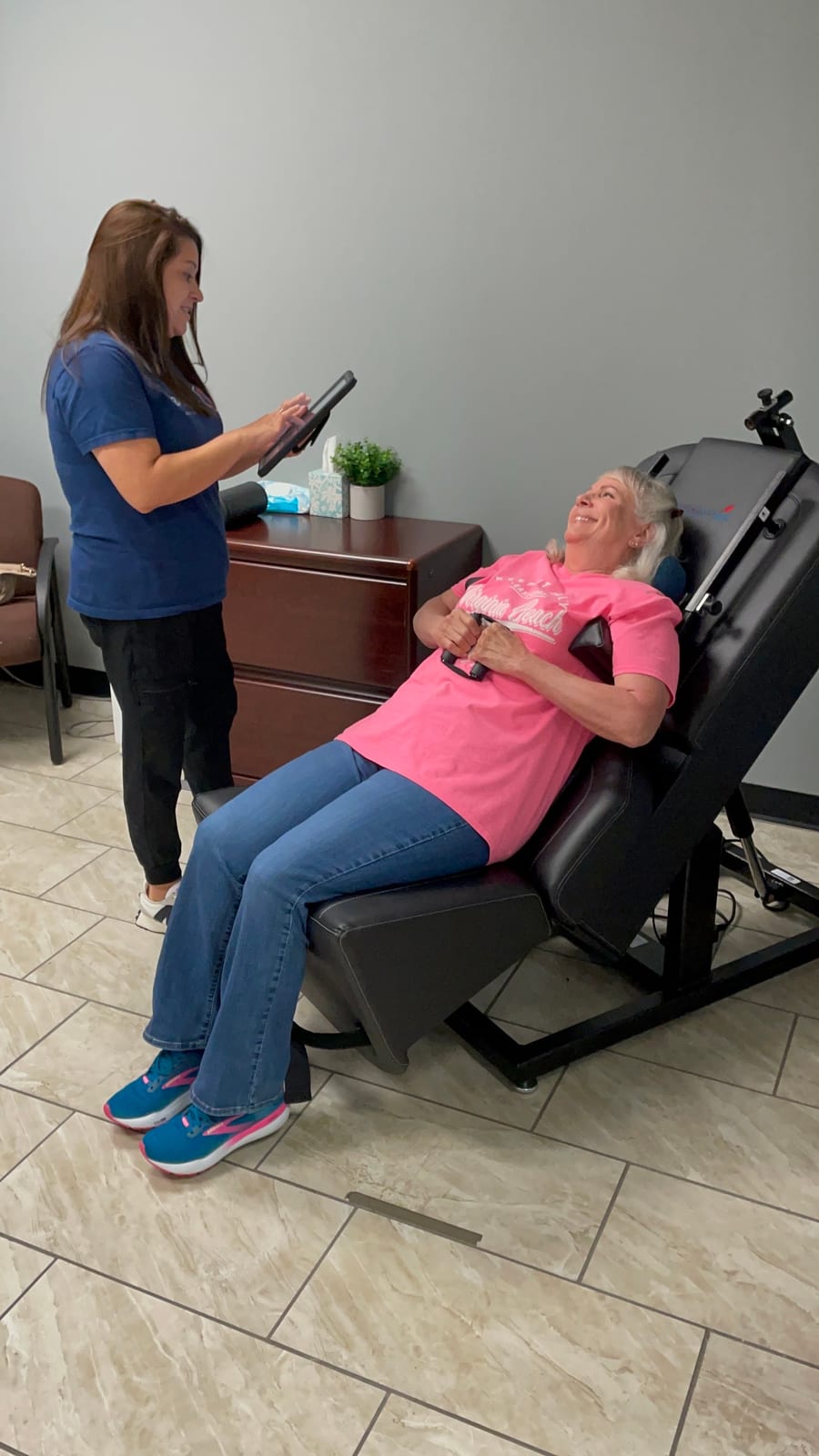 A patient reclined comfortably in the seated treatment chair, talking with a clinic team member